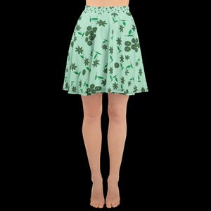 May include: A light green skater skirt with a floral pattern. The skirt features a repeating design of dark green flowers and leaves on a light green background. The skirt is flared and falls above the knees.