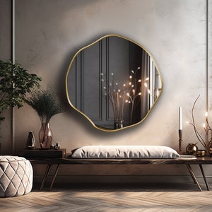 Circular Asymmetrical Mirror with gold frame hung on the wall of an entryway.