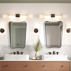 Two Italian Mirrors with black frame hung on the wall of a bathroom above a double vanity.