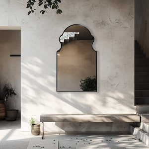 Bohemian Arched Mirror with black frame finish hang on the wall of an entryway over a stone bench.