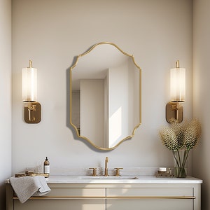 Quatrefoil mirror with gold frame hung over the wall of a bathroom.