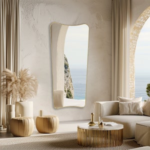 Italian mirror with gold frame hung on the wall of a terrace, next to the sea.