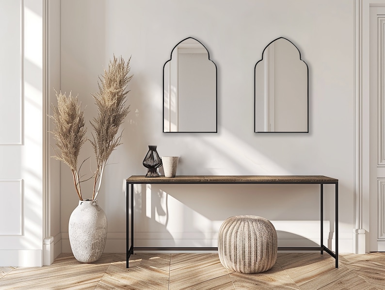 Two Accent Mirrors with black frame finish hung on the wall of an entryway over a console.