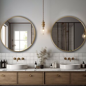 Two round mirrors with gold finish hung on the wall of a bathroom over a vanity.