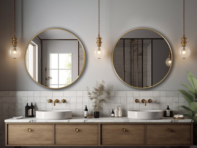 Two round mirrors with gold finish hung on the wall of a bathroom over a vanity.