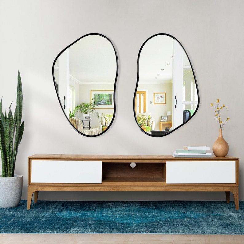 Two kidney shape mirrors with black frame hung on the wall of a living room.