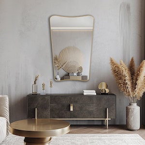 Italian butterfly mirror with gold frame hung on the wall of a living room.