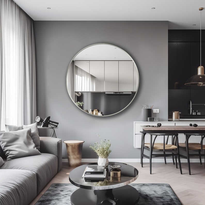Round mirror with silver finish hung on the wall of a living room.