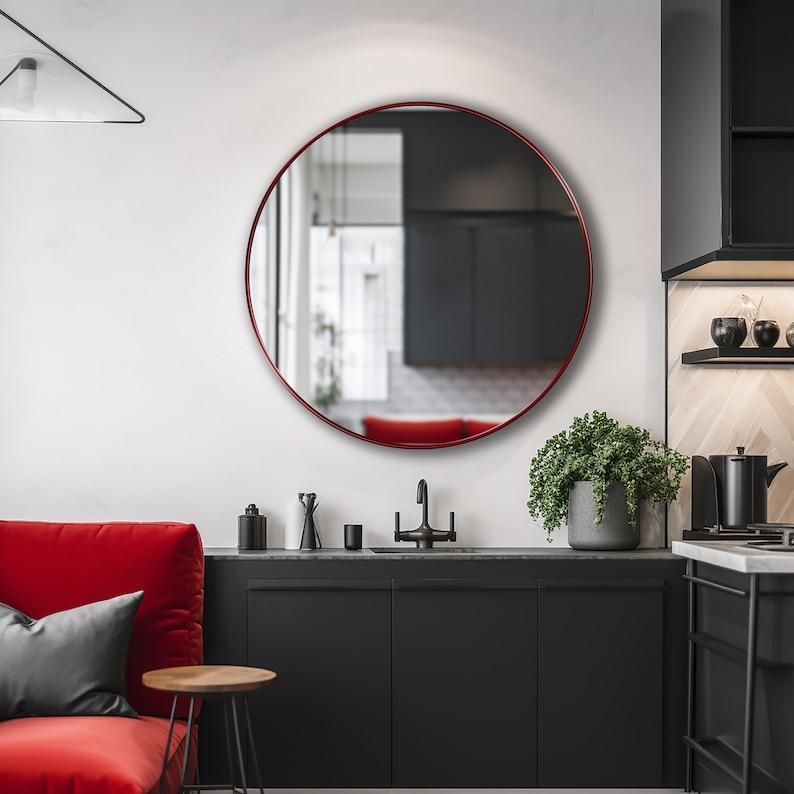 Round mirror with red finish hung on the wall of a kitchen.