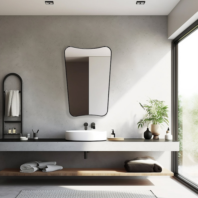 Italian Mirror with black frame hung on the wall of a bathroom above a vanity.