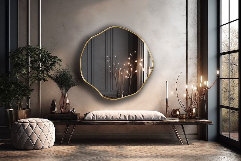 Circular Asymmetrical Mirror with gold frame hung on the wall of an entryway.