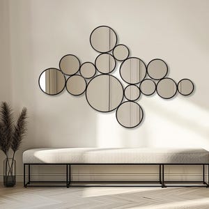 May include: A modern wall decor arrangement featuring a collection of circular mirrors with black frames. The mirrors are of varying sizes and are arranged in a cluster. Below, a neutral-toned bench with a black metal frame adds to the contemporary aesthetic.