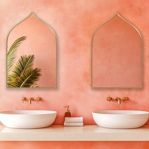 Two Sahara Mirrors with gold frame finish hung on the wall of a bohemian bathroom over a double vanity.