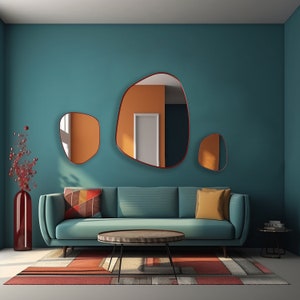 Three asymmetrical mirrors with red frame hung on the wall of a spacious living room over a big sage color couch.