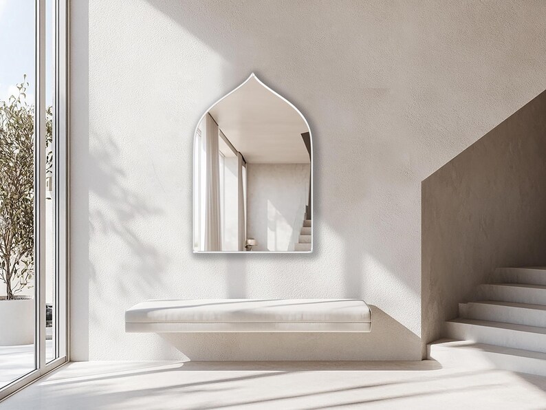 Sahara Mirror with emerald frame finish hung on the wall of an entryway.