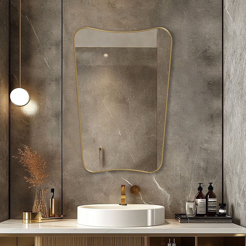 Italian mirror with gold frame hung on the wall of a bathroom.