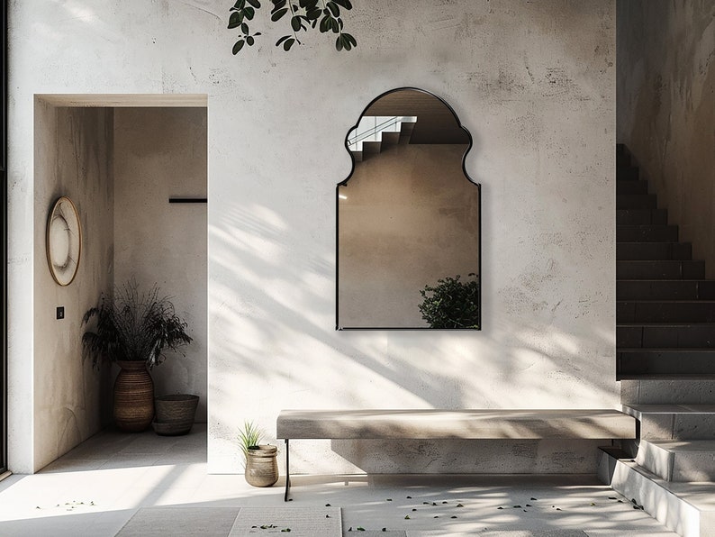 Bohemian Arched Mirror with black frame finish hang on the wall of an entryway over a stone bench.