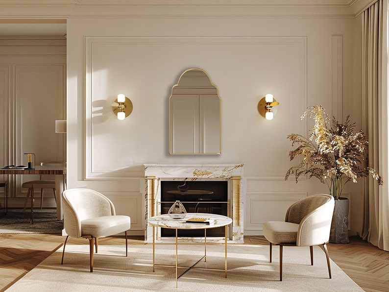 Arched Moroccan Mirror with gold frame finish hung on the wall of a living room over a fireplace.