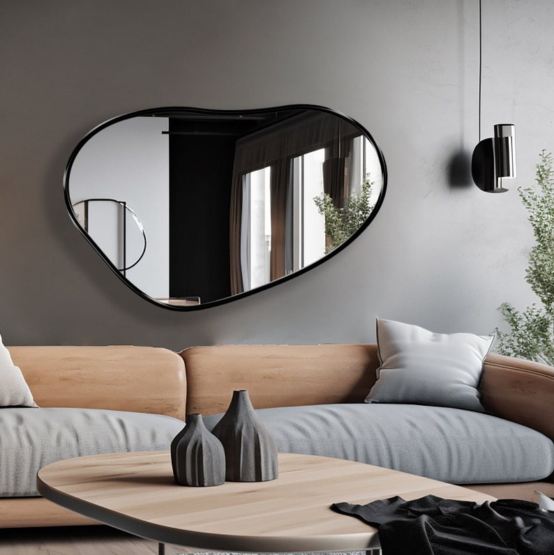 Kidney mirror with black frame hung on the wall of a living room.