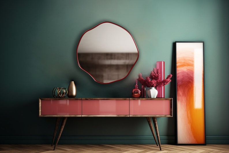 Circular Asymmetrical Mirror with red frame hung on the wall of an entryway.