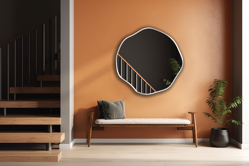 Circular Asymmetrical Mirror with white frame hung on the wall of an entryway.