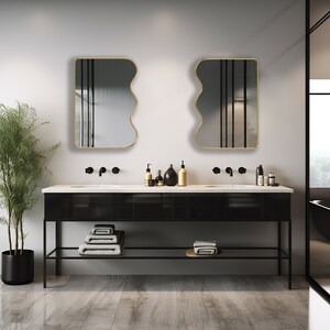 Two squiggle mirrors with gold frame hung on the wall of a powder room.