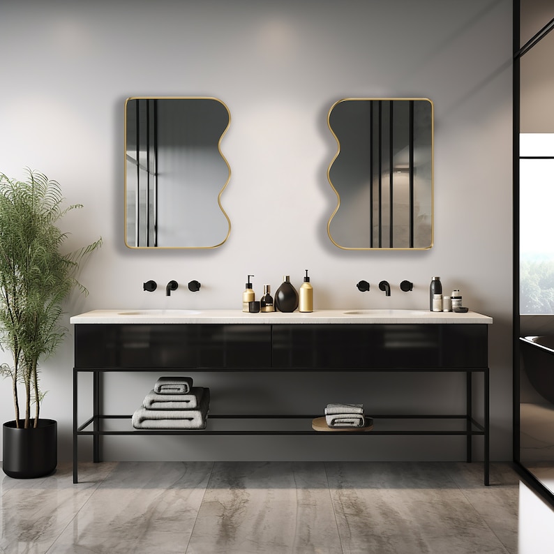 Two squiggle mirrors with gold frame hung on the wall of a powder room.