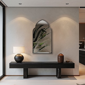 Accent Mirror with black frame finish hung on the wall of an entryway over a console.