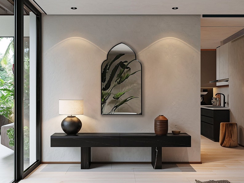 Accent Mirror with black frame finish hung on the wall of an entryway over a console.