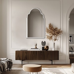 Arched Moroccan Mirror with white frame finish hung on the wall of a living room over a console.