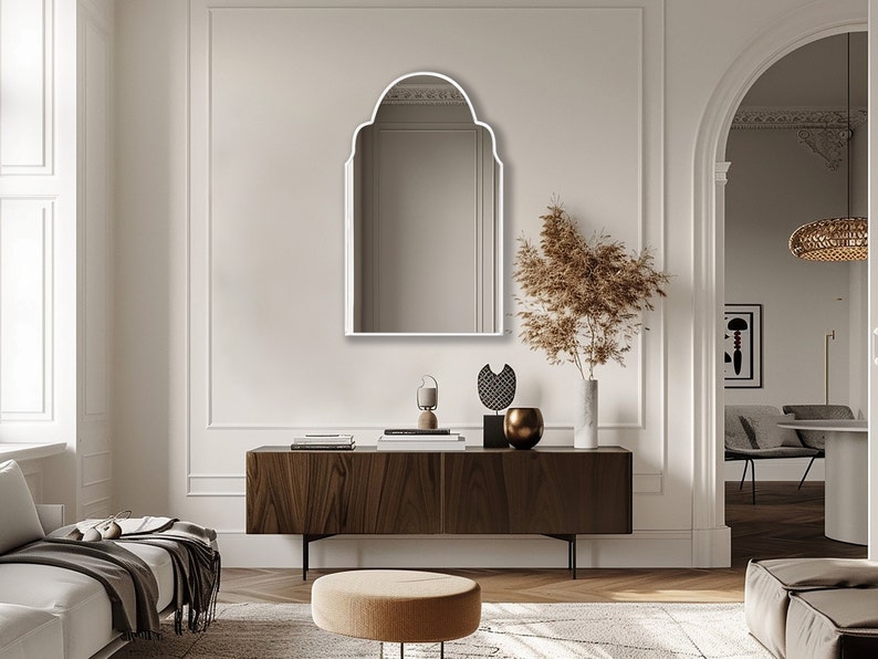 Arched Moroccan Mirror with white frame finish hung on the wall of a living room over a console.