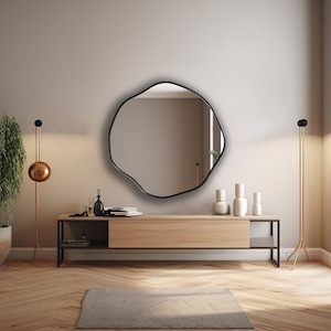 Circular Asymmetrical Mirror with black frame hung on the wall of an entryway.