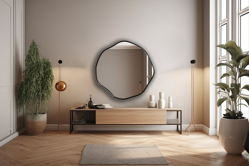 Circular Asymmetrical Mirror with black frame hung on the wall of an entryway.