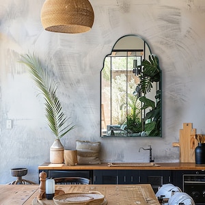 Arched Moroccan Mirror with emerald frame finish hung on the wall of a kitchen over a sink and dining table.