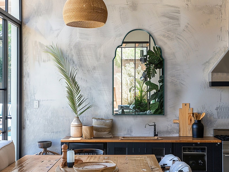 Arched Moroccan Mirror with emerald frame finish hung on the wall of a kitchen over a sink and dining table.