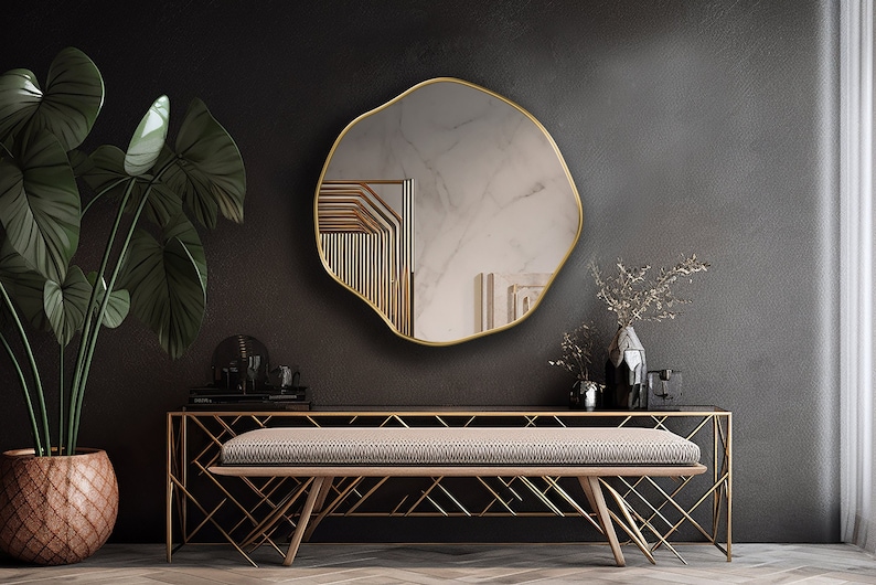 Circular Asymmetrical Mirror with gold frame hung on the wall of an entryway.