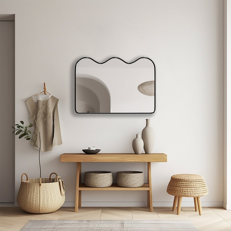 Squiggle mirror with black frame hung on the wall of an entryway.