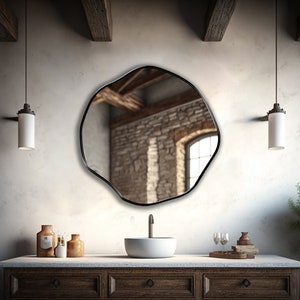 Circular Asymmetrical Mirror with Black Frame hung on the wall of a hallway.