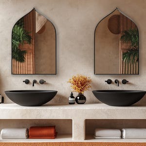 Two Sahara Mirrors with black frame finish hung on the wall of a bohemian bathroom over a double vanity.