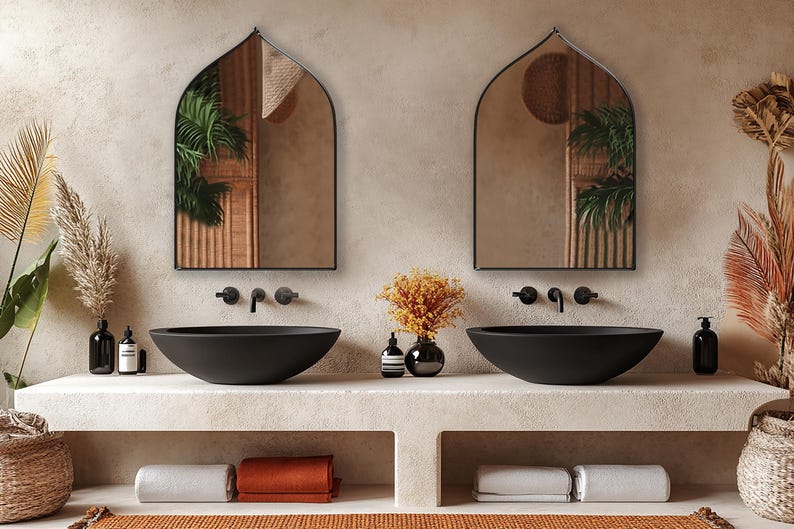 Two Sahara Mirrors with black frame finish hung on the wall of a bohemian bathroom over a double vanity.