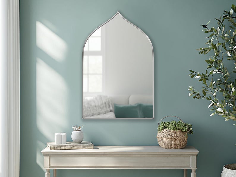 Sahara Mirror with silver frame finish hung on the wall of an entryway over a console.