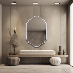 Quatrefoil mirror with white frame hung over the wall of an entryway.