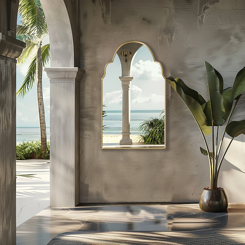 Arched Moroccan Mirror with gold frame finish hung on the wall of a beach house.