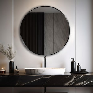 Round mirror with black finish hung on the wall of a bathroom over a vanity.
