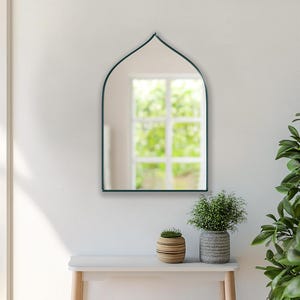 Sahara Mirror with emerald frame finish hung on the wall of an entryway.
