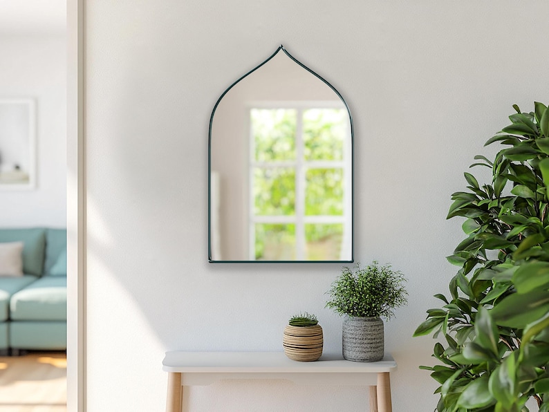 Sahara Mirror with emerald frame finish hung on the wall of an entryway.