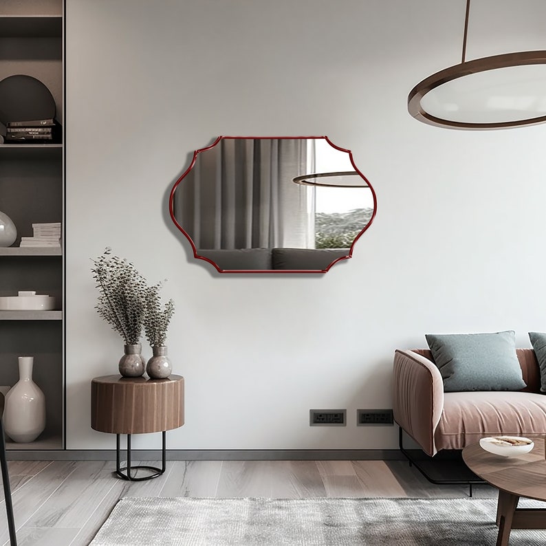 Quatrefoil mirror with red frame hung over the wall of a living room.