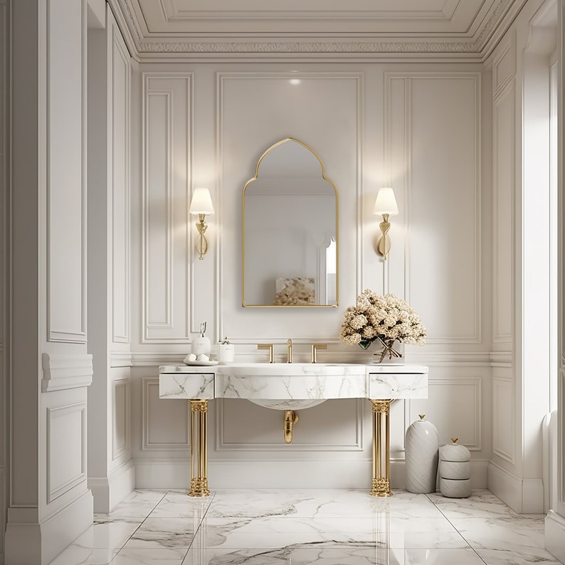 Accent Mirror with gold frame finish hung on the wall of an powder room over a vanity.