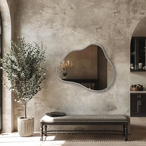 Organic Pebble Mirror with silver frame finish hung on the wall of an entryway, over a bench.