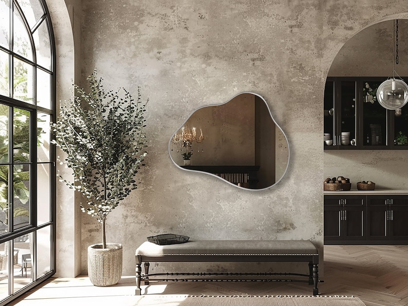 Organic Pebble Mirror with silver frame finish hung on the wall of an entryway, over a bench.